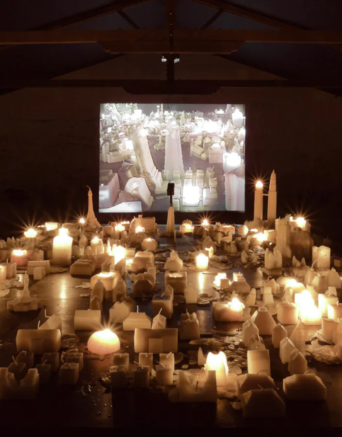 Carlos Garaicoa, Ahora Juguemos a Desaparecer (II), 2002, mesa de metal, velas, instalação de vídeo, dimensões variáveis. Foto: Eduardo Eckenfels