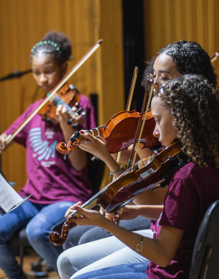 Estudantes e suas famílias conhecem a estrutura da Escola de Música Inhotim e assistem à apresentação de concerto didático com pessoas professoras. 